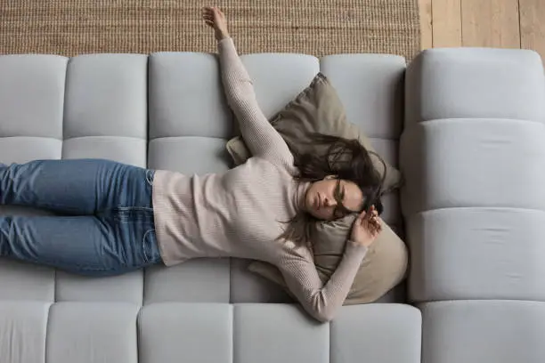 Photo of Sleepy girl in casual clothes resting on couch at home