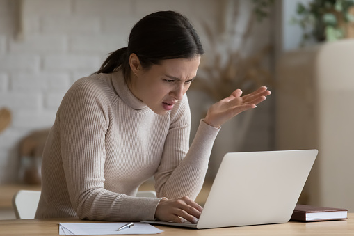 Concerned annoyed computer user girl staring at laptop screen with angry face, having problems with software, online app, banking service, getting bad news, feeling stress about connection errors