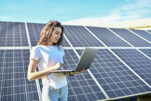 Focused Female Expert On Solar Panels Checking Cell Condition On Laptop stock photo