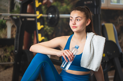 A woman drinks water during training. Stock photo