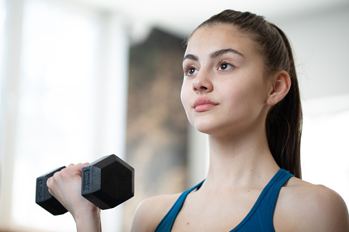 A girl lifting weights in the gym.