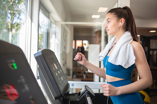 Young woman running on treadmill at the gym