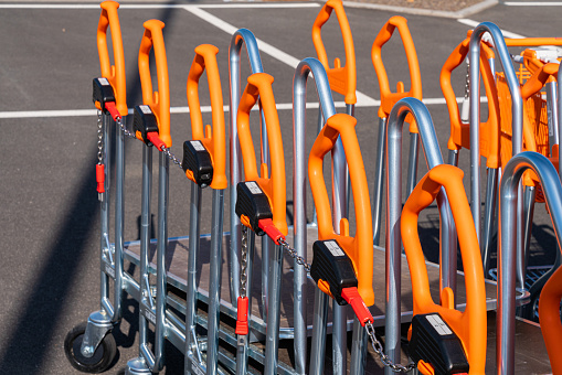 Shopping trolleys with orange handles lined up at hardware store. Closeup.