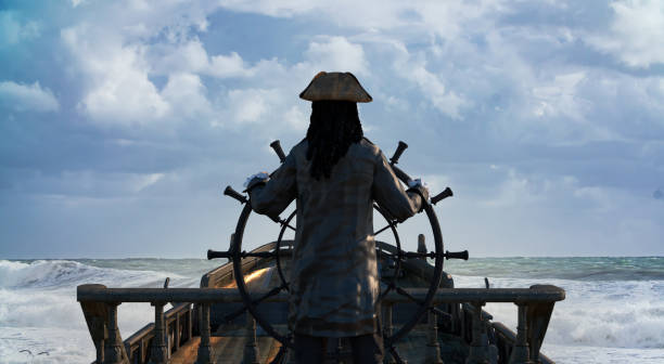 le capitaine pirate tient le volant du navire et navigue à travers la mer sur un voilier pirate render 3d - capitaine photos et images de collection