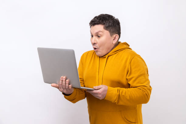 istock Astonished man working on laptop typing email or chatting in social network, shocked face expression 1405694871