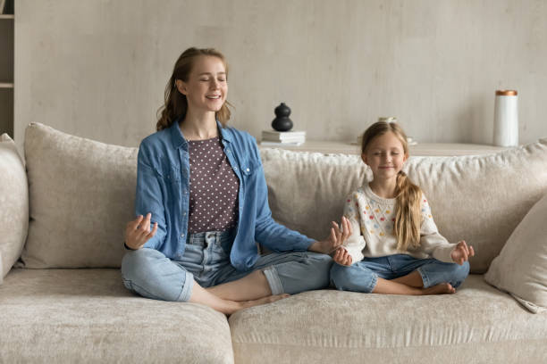 entspannte, friedliche junge mutter und kleine tochter, die yoga-übungen machen. - yoga good posture women little girls stock-fotos und bilder