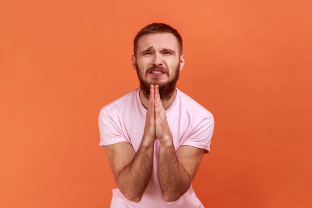 Man folding hands in prayer, closing eyes and talking to god, asking for help, expressing gratitude.