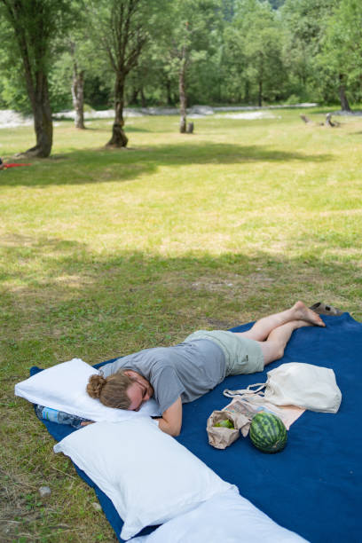 istock Young man rests on picnic blanket in public park 1405696115