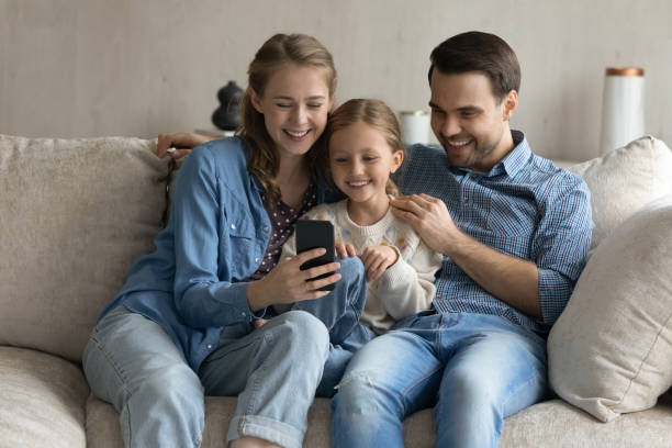 istock Affectionate couple parents and little daughter using cellphone. 1405696138