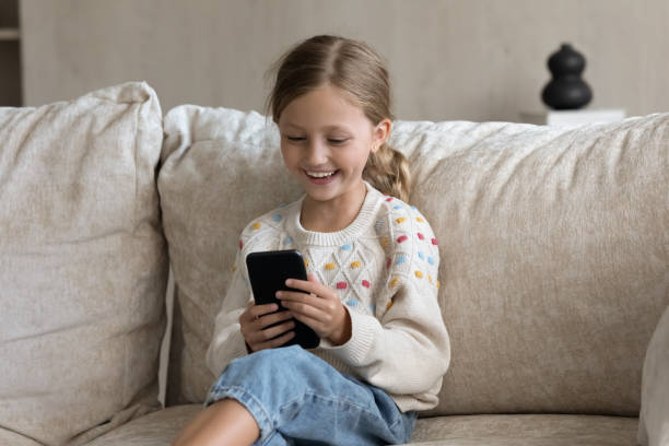 istock Happy small girl using cellphone at home. 1405696173