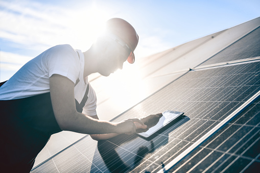 Sunlight Falling Over Male Worker Using Digital Tablet To Calibrate Solar Panel