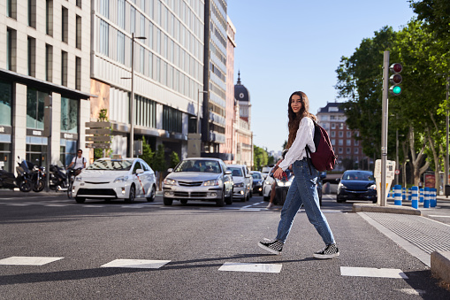female tourist crossing a crosswalk in Madrid. young Caucasian woman at sunset.