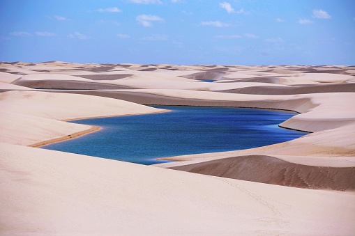 Lagoon of intense blue water and white sand of the dunes of Lençóis Maranhenses, Brazil.