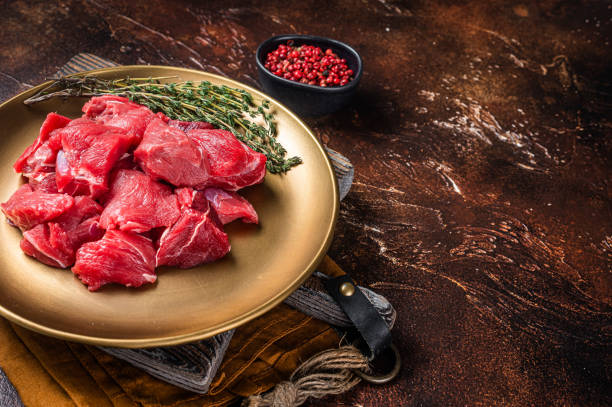 istock Raw diced lamb mutton meat with thyme. Dark background. Top view. Copy space 1405698983