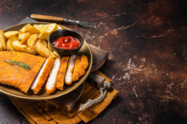 breaded german weiner schnitzel with potato wedges. dark background. top view. copy space - weiner schnitzel imagens e fotografias de stock