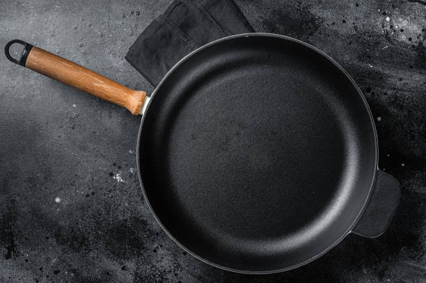 istock Empty cast-iron skillet for cooking  on rustic towel. Black background. Top view. Copy space 1405700212