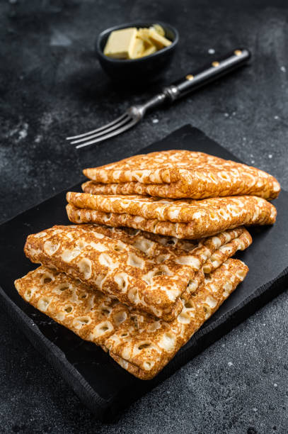 istock Stack of crepes with butter on a marble board. Black background. Top view 1405701947