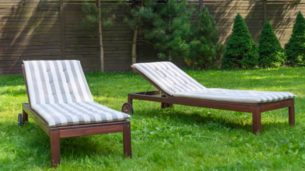 istock Lounge chairs on the backyard in a beautiful garden. Two empty sunbeds on the grass. 1405703367