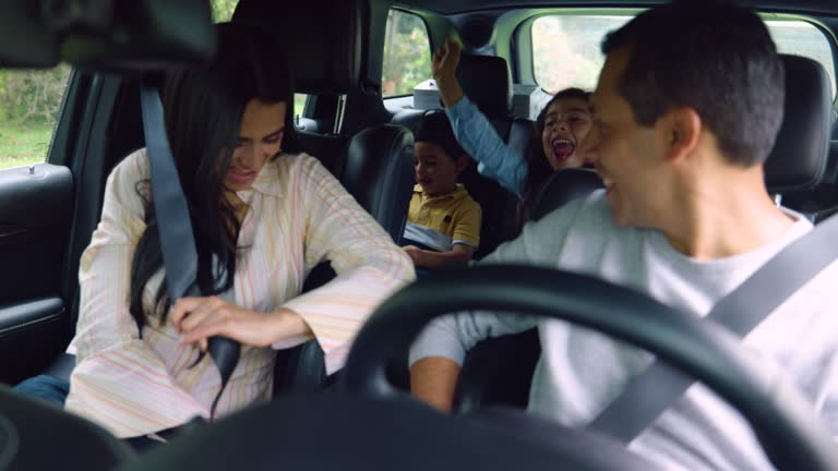 Beautiful Latin American family with two children fastening their seat belts ready for a road trip all looking very excited - Lifestyles
