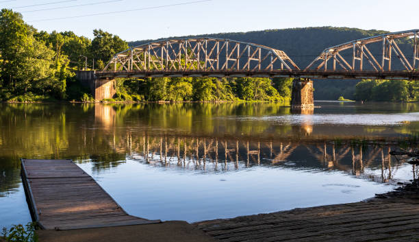 A wooden dock in the Allegheny River with the Tidioute Bridge in the background stock photo