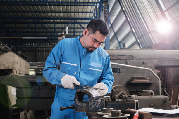 One professional Asian male worker works in metalwork manufacturing factory. stock photo