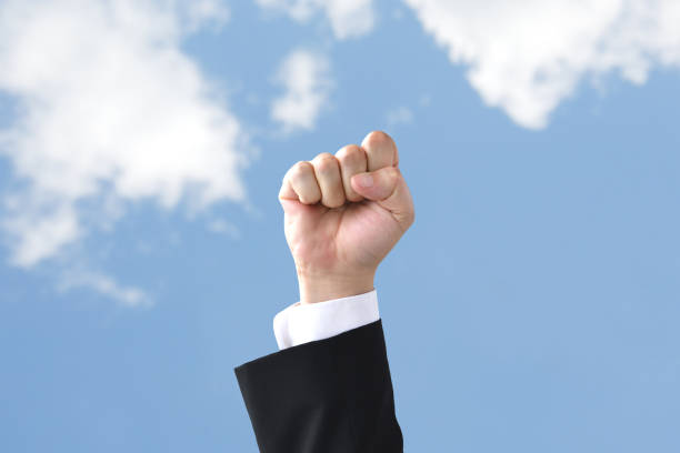 istock Businessman's hand raised in blue sky 1405723210