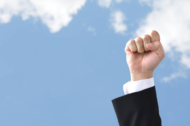 Businessman's hand raised in blue sky