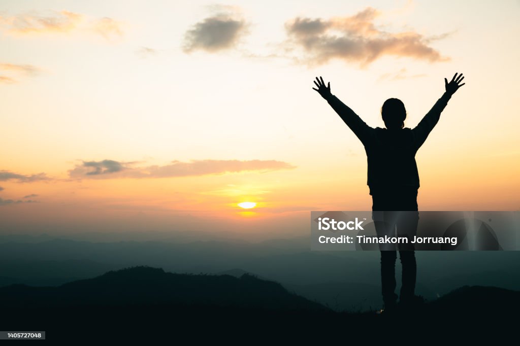 silhouette of a woman praying on the mountain, Praying hands with faith in religion and belief in God. Conquering Adversity Stock Photo