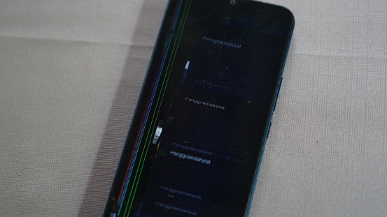 Broken smartphone screen on the table with gray background