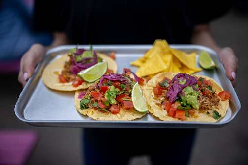 Close-up on a waitress serving tacos at a Mexican Restaurant - food service concepts