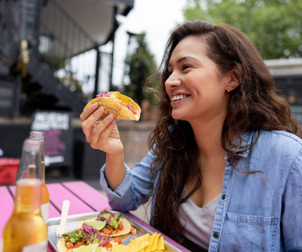 donna felice che mangia tacos in un ristorante - spanish culture women latin american and hispanic ethnicity mexican culture foto e immagini stock