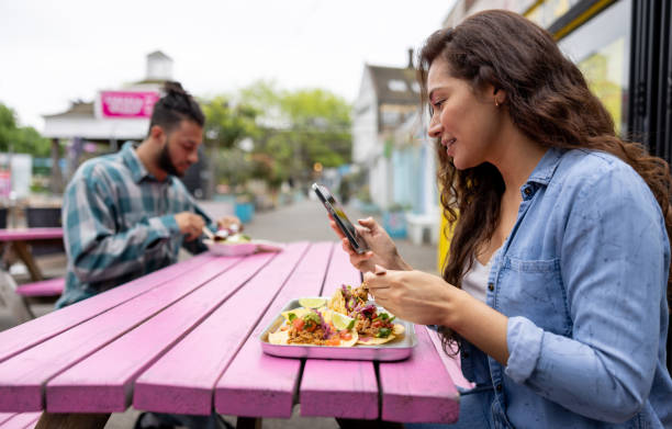istock Woman texting on her phone while eating some tacos 1405734628