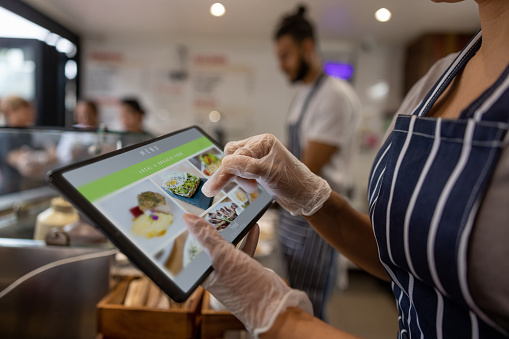 Close-up on a waitress using a tablet to take an order at a restaurant - food service concepts