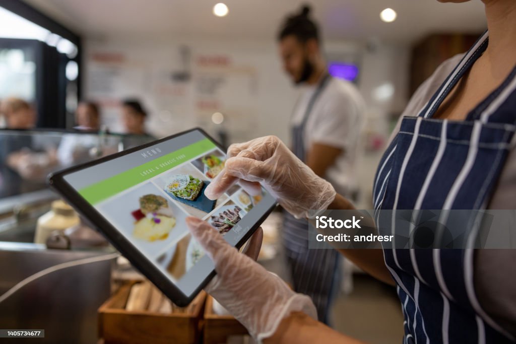 Close-up on a waitress using a tablet to take an order at a restaurant Close-up on a waitress using a tablet to take an order at a restaurant - food service concepts Point Of Sale Stock Photo