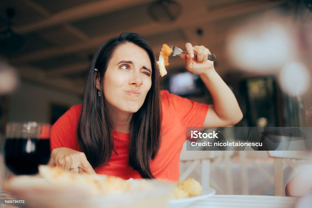 Exigent Woman Over Analyzing Food Course in a Restaurant Worried customer suffering from orthorexia worried about cholesterol Critic Stock Photo