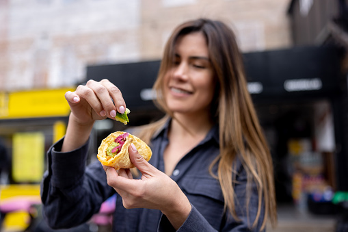 Happy woman eating tacos and squeezing a lime on top â street food concepts