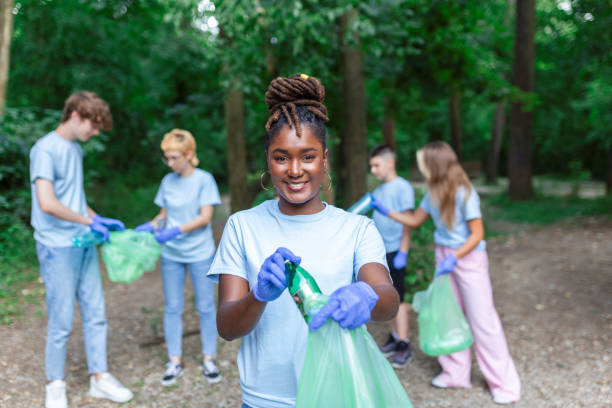 un groupe de jeunes amis bénévoles ramassent des bouteilles en plastique pour en faire des sacs poubelles dans la forêt. concept d’écologie - bag garbage bag plastic black photos et images de collection