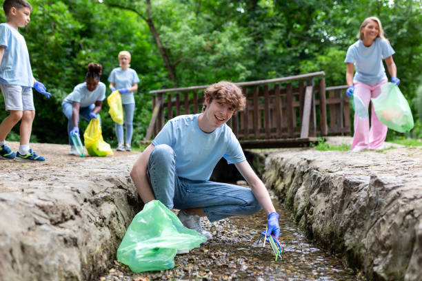 istock Man handpicking gathering up garbage plastic straws garbage from the river at the park. World environment day.Environment concept. 1405738046