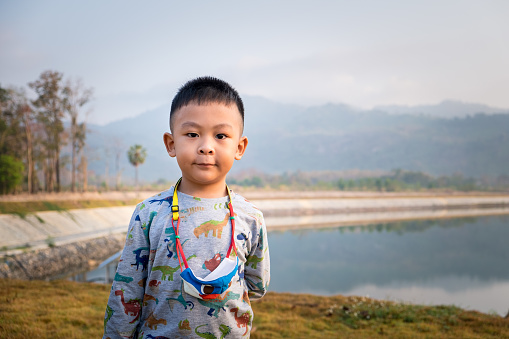 Cute little Asian child smiling in the big mountain outdoors. Happy boy playing while on vacation in the summer holiday. Kids laugh in the pool on the quiet hill. Children standing in the nature.