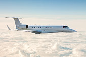 White business jet flies in the air above the clouds