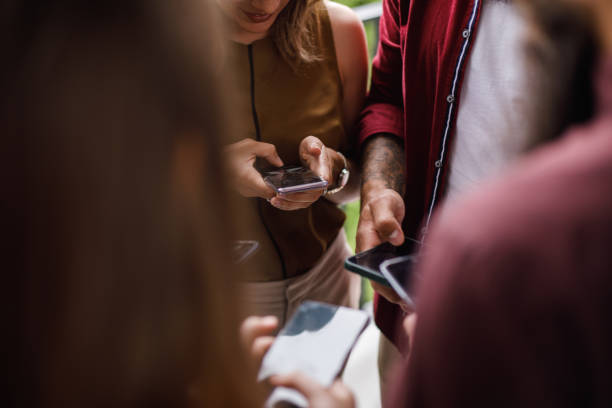 istock People standing in closed circle, exchanging data on their smart phones 1405745636