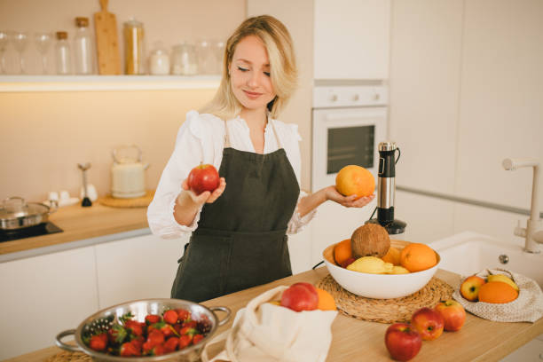 istock Millennial woman preparing ingridients for making smoothies at the kitchen 1405747806