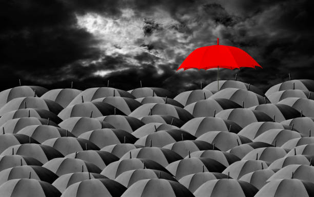 istock Red umbrella surrounded by many black umbrellas against dark cloudy sky 1405751375