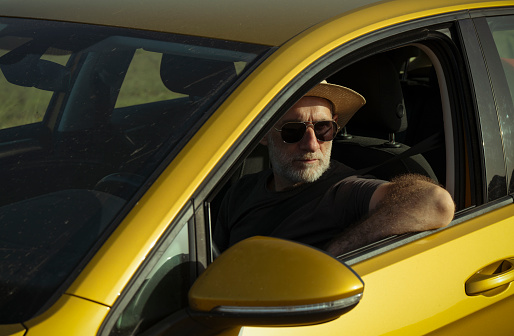 Adult man in hat and sunglasses in car