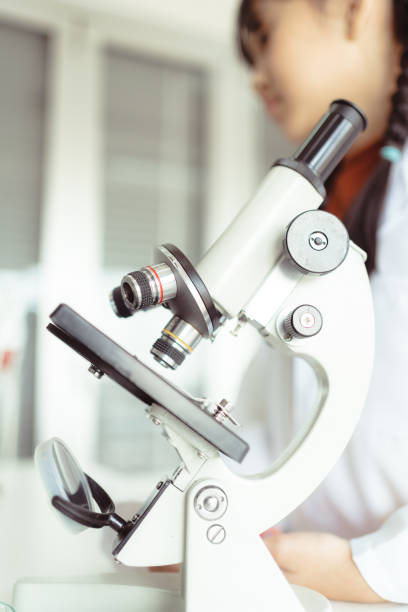 Microscope closeup in a school laboratory in Bangkok, Thailand with students in the background.