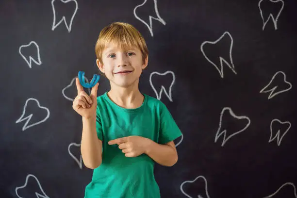 Photo of Six-year old boy shows myofunctional trainer. Helps equalize the growing teeth and correct bite, develop mouth breathing habit. Corrects the position of the tongue