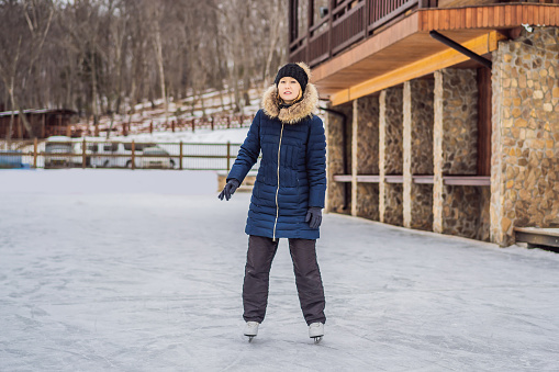 happy beautiful girl wearing warm winter clothes ice skating.