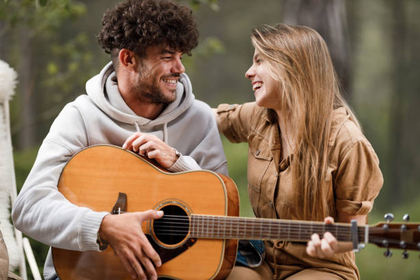 istock Happy couple talking while playing a guitar in nature. 1405753143