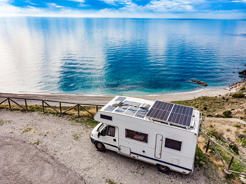 Caravan with solar panels on roof camping on cliff sea coast. Mediterranean region of Nerja, Costa del Sol in Andalusia, Spain.
