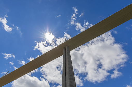 Aveyron - France. June 30, 2021: One of concrete pylon of Millau viaduct supports road on background with bright sunny sky with silk clouds. Aveyron, Occitania, France